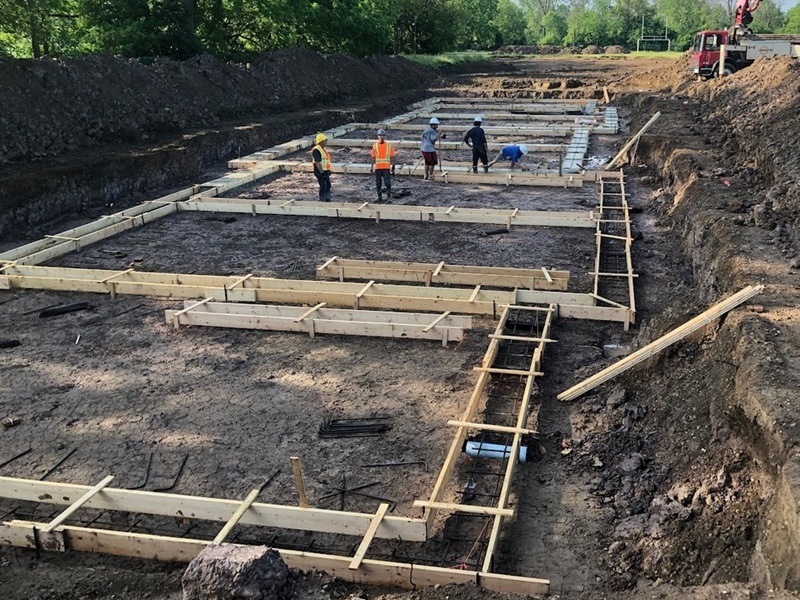 Construction crew installing concrete footing forms at an excavated building site